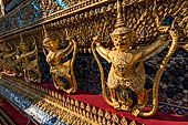 Bangkok Grand Palace,  Wat Phra Keow (temple of the Emerald Buddha). Golden garudas holding nagas support the external wall of the ubosot. 